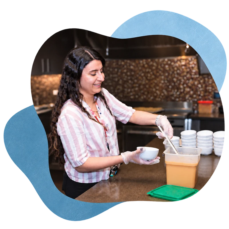A Treasure House resident working behind a counter in a layered blue composition