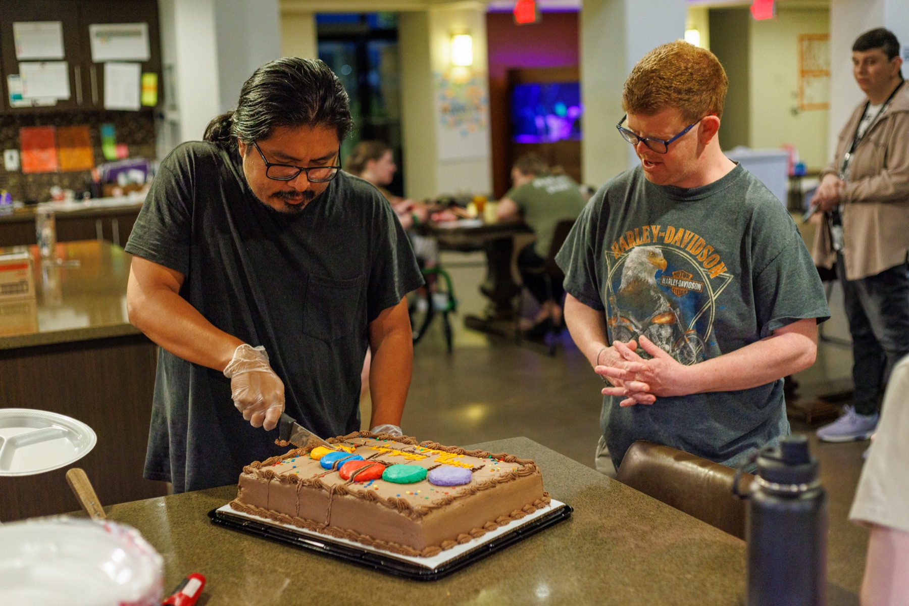 A resident and a staff member decorating a cake together in the Treasure House kitchen