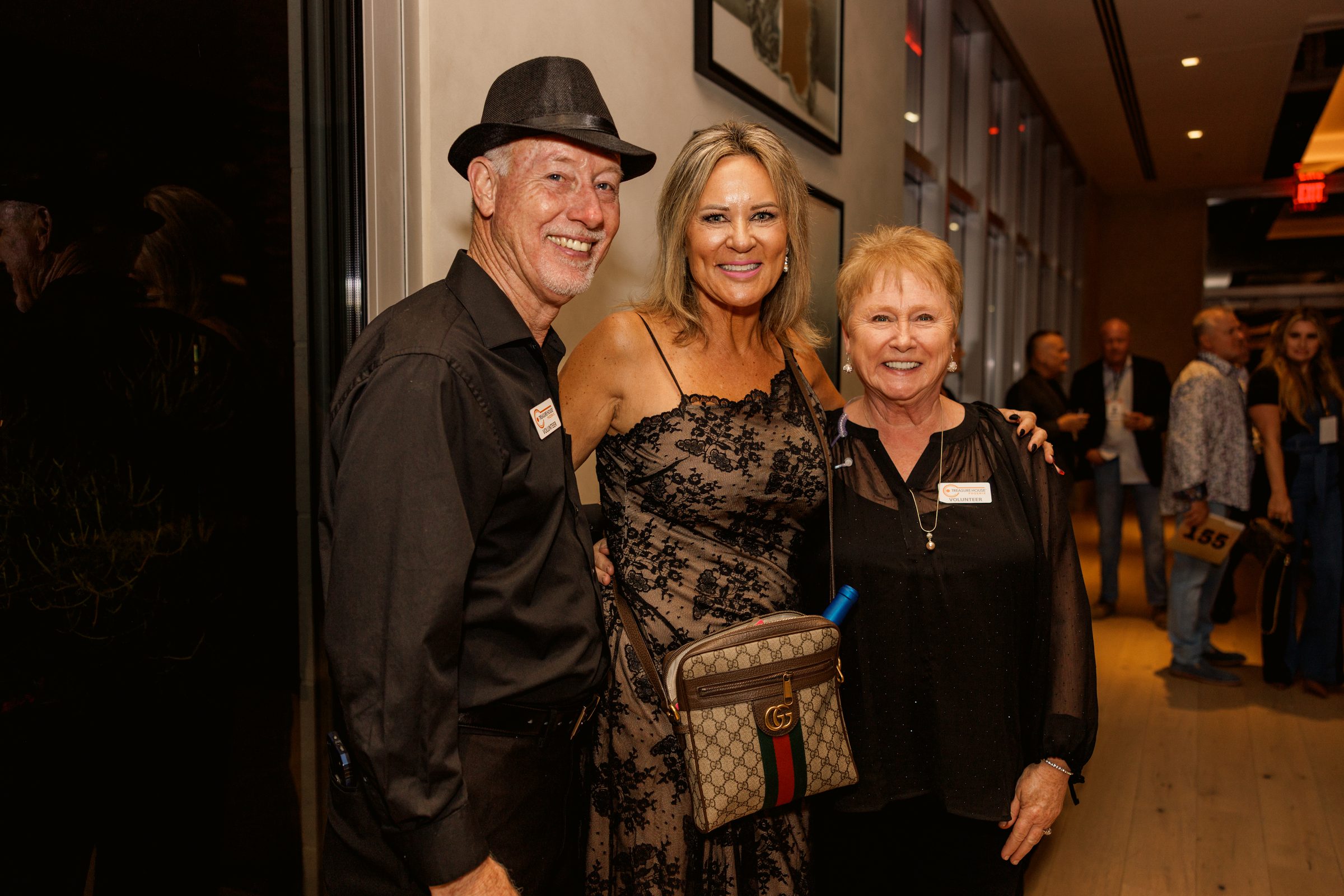 Three volunteers in name badges at an evening Treasure House event
